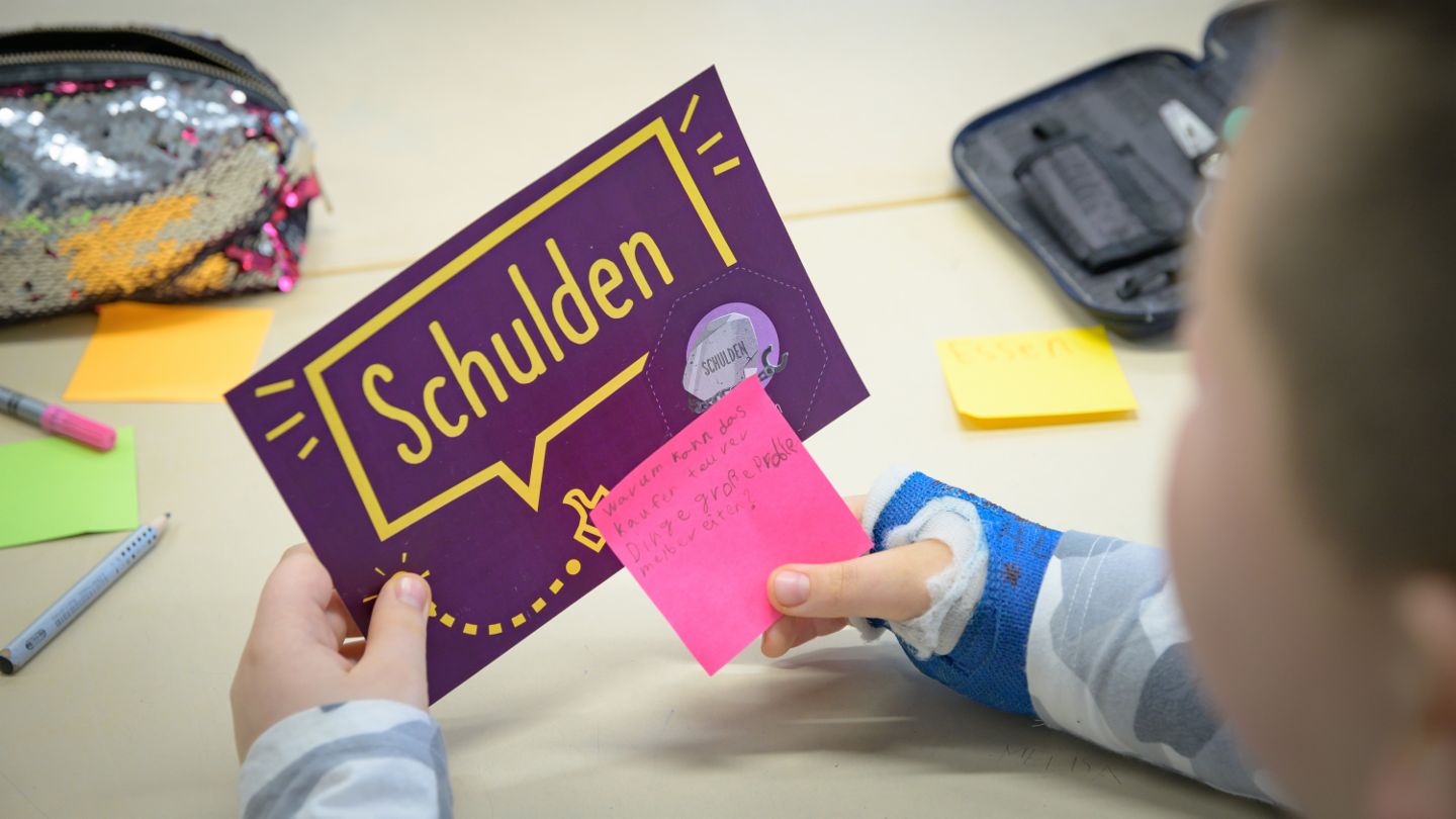 Financial education for children: Child looks at a flash card on the topic of debt.