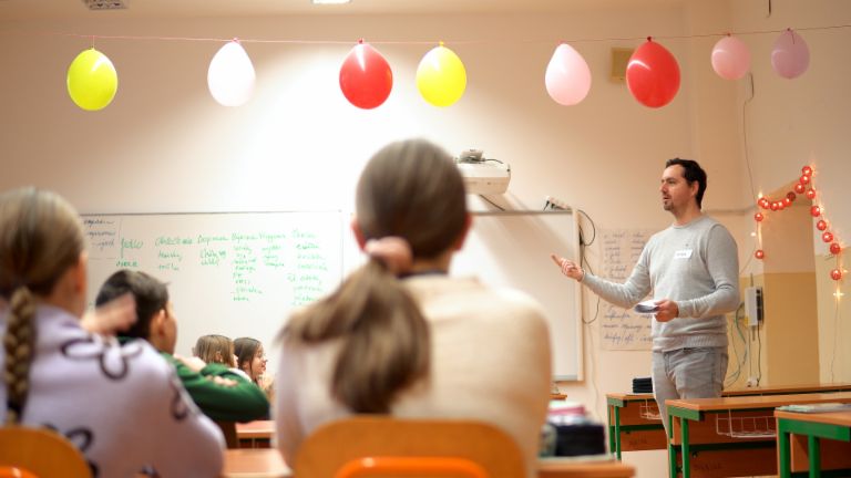  Deti sedia v triede a počúvajú mužského učiteľa hovoriť o finančnom vzdelávaní.