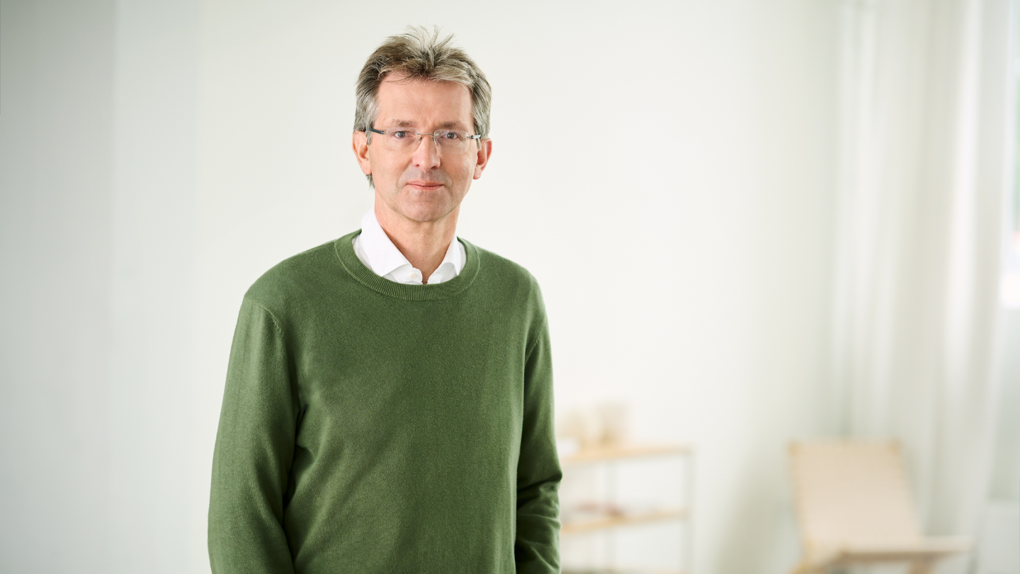 Justus Hecking-Veltman, CFO, stojaci v zelenom svetri a bielej košeli vo svetlej miestnosti.