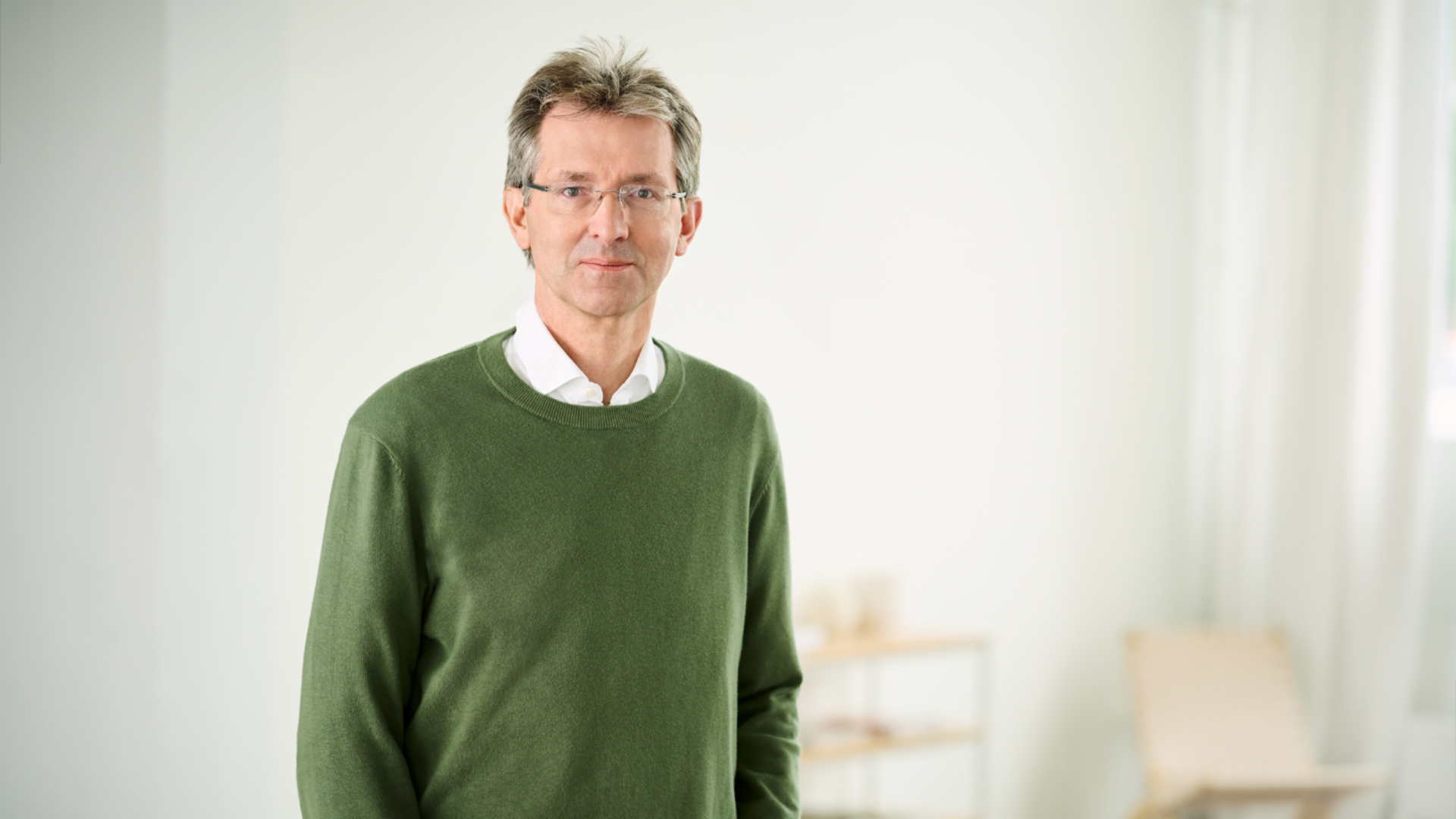 Justus Hecking-Veltman, CFO, stojaci v zelenom svetri a bielej košeli vo svetlej miestnosti.