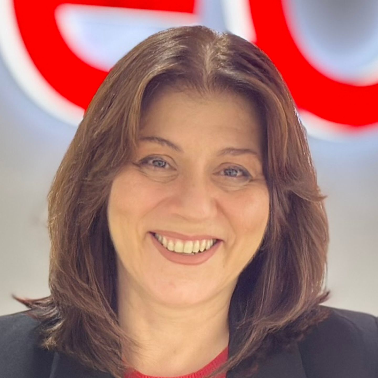 Belén Barreiro, agent kontaktného centra spoločnosti EOS v Španielsku, sa opiera o pult v čiernom saku pred jasným logom EOS.