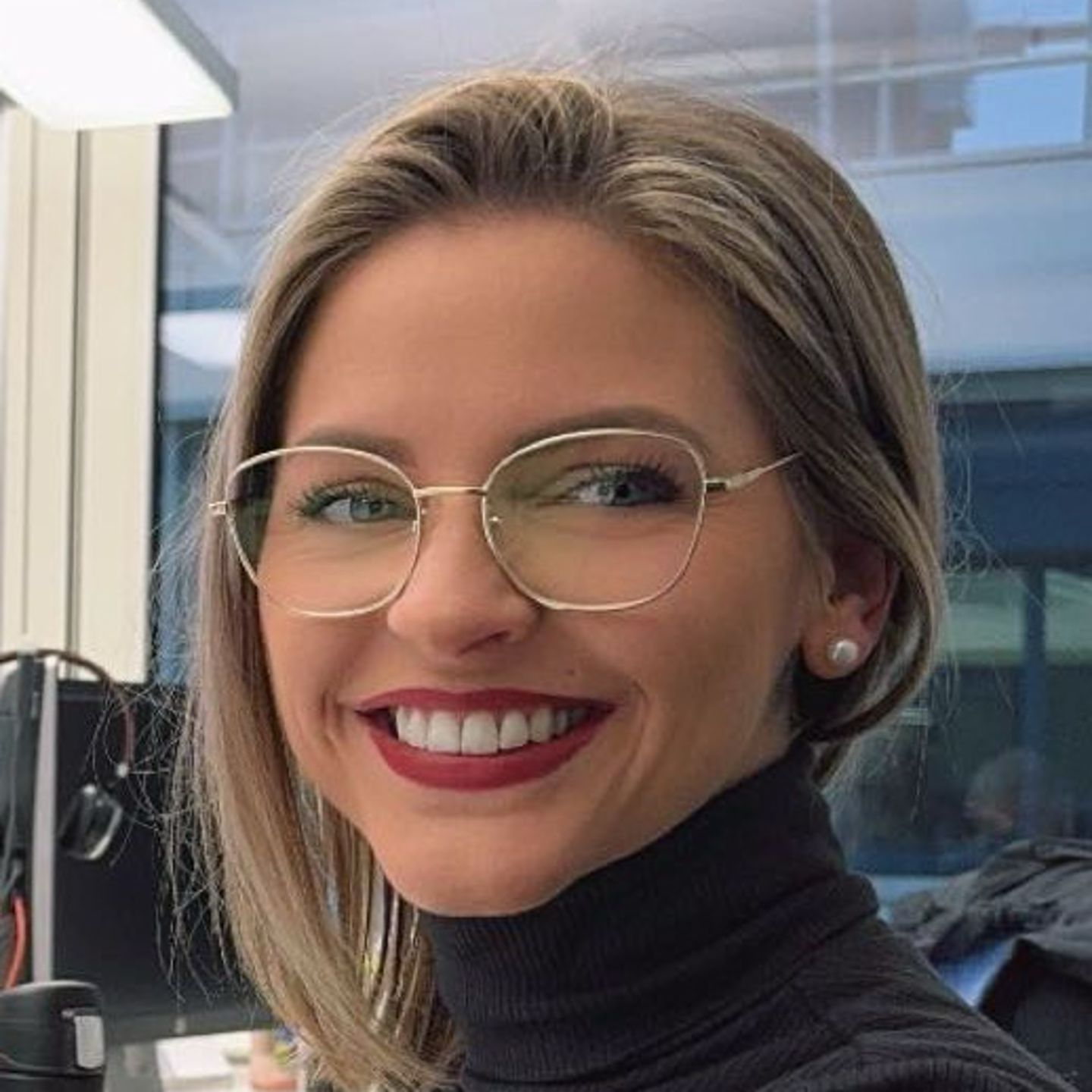 Genny Bollingerová, špecialistka na reštrukturalizáciu dlhu zo spoločnosti EOS vo Švajčiarsku, sedí za stolom v sivom rolákovom svetri a usmieva sa do kamery.