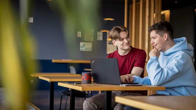 Dvaja zamestnanci spolupracujú pri notebooku a podporujú partnerstvo a férovosť na pracovisku.