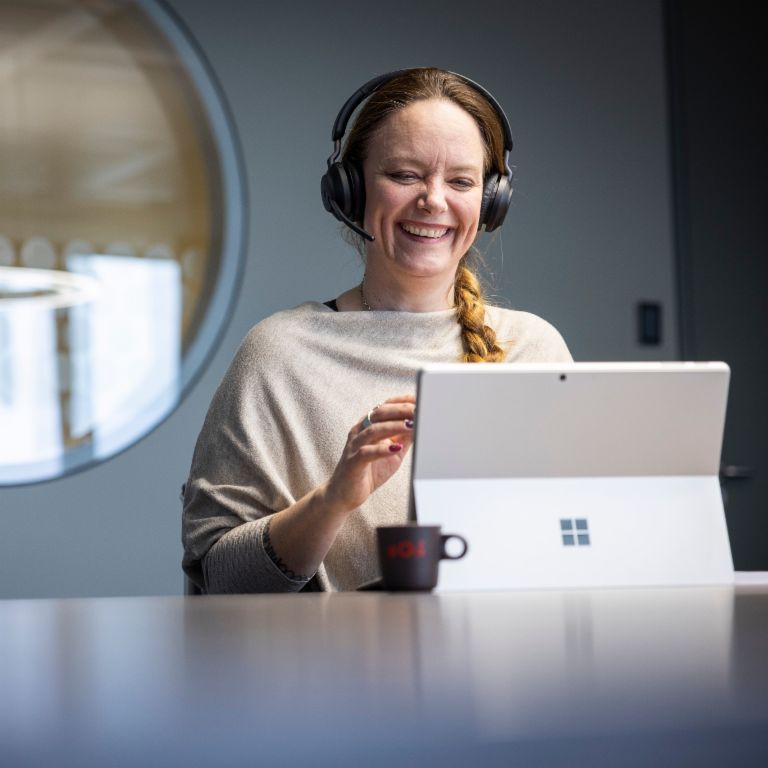 Zamestnanec EOS má na sebe headset a je vidieť, ako sa usmieva počas rozhovoru s digitálnym partnerom.