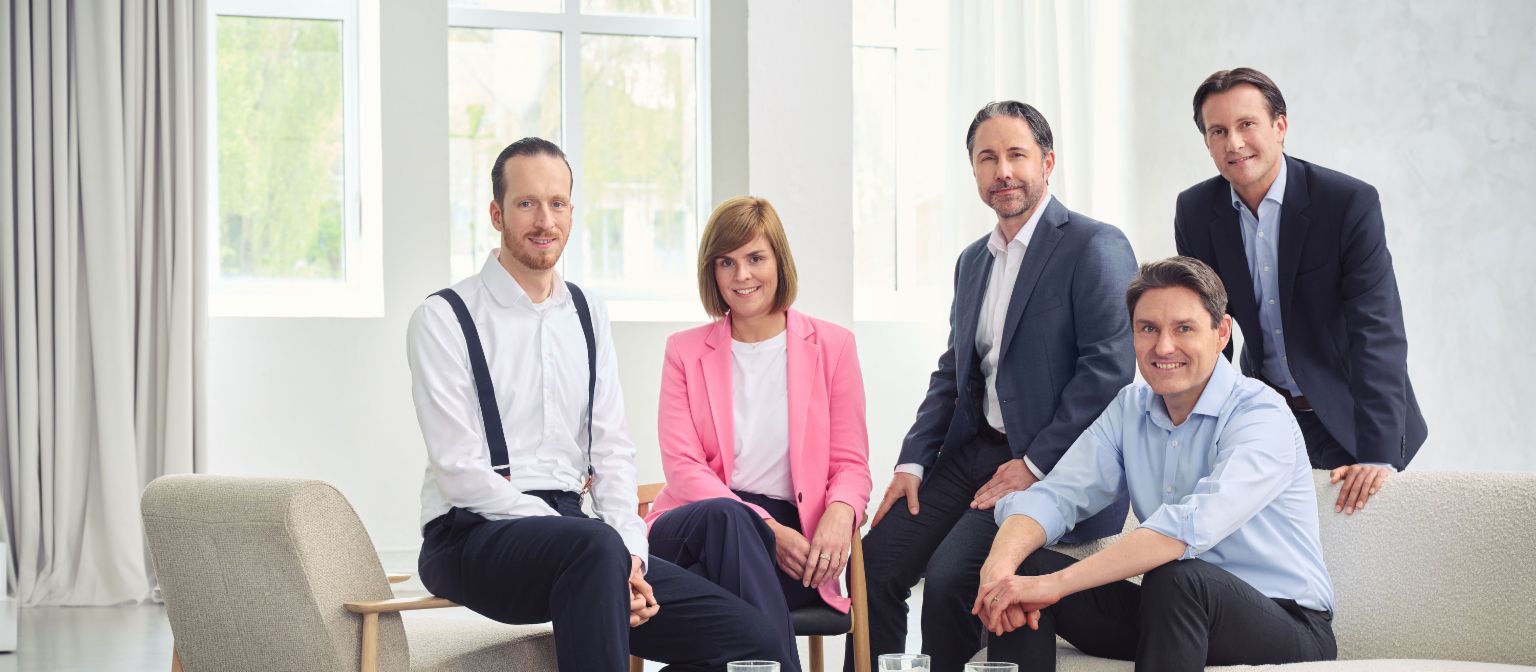 Predstavenstvo skupiny EOS (zľava doprava: Sebastian Pollmer, Dr. Eva Griewel, Marwin Ramcke, Dr. Stephan Ohlmeyer, Carsten Tidow), pozerajú priamo do objektívu v svetlej miestnosti