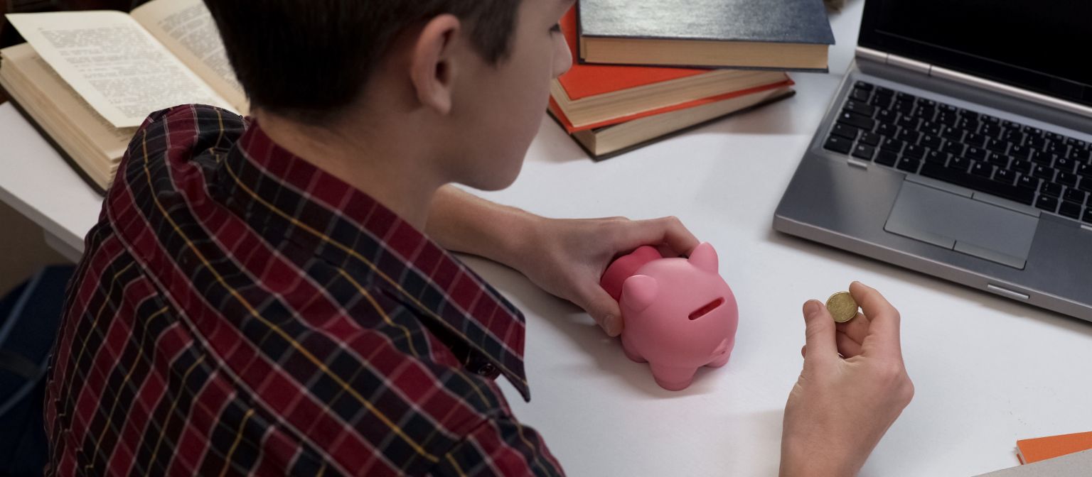 boy putting change into a piggy bank.