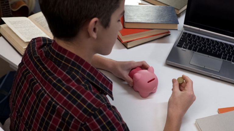 boy putting change into a piggy bank.